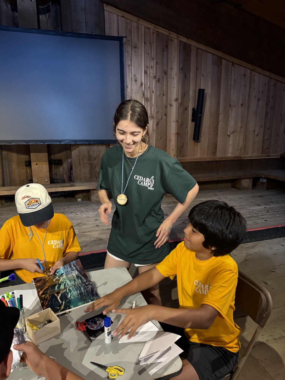 A volunteer smiles at two students.